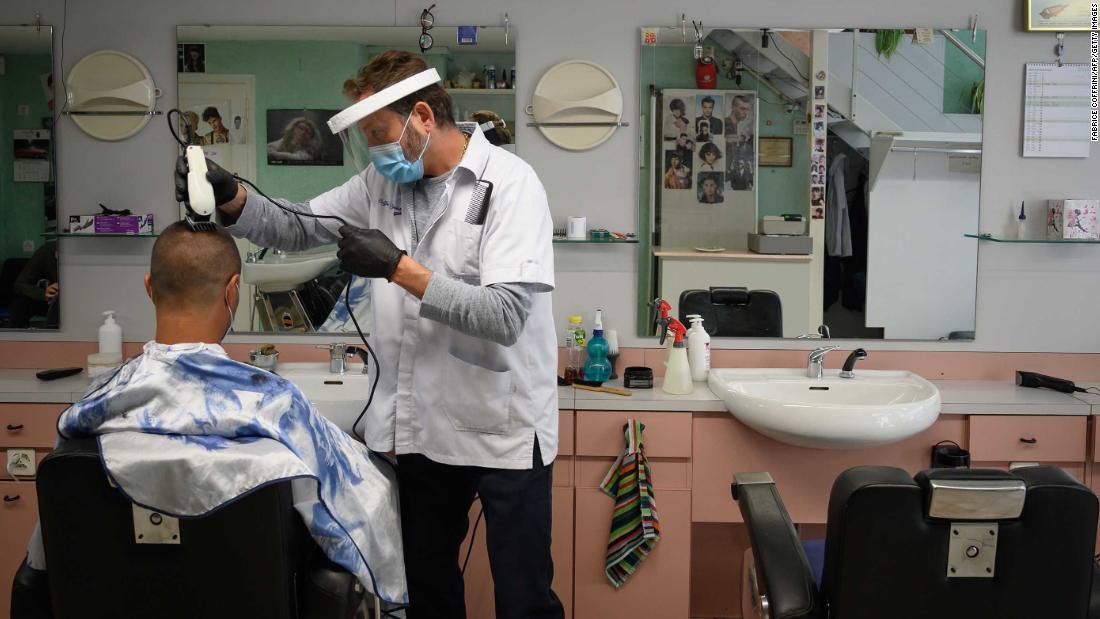 A barber wears protective equipment as he cuts a customer&#39;s hair in Lausanne, Switzerland, on April 27.